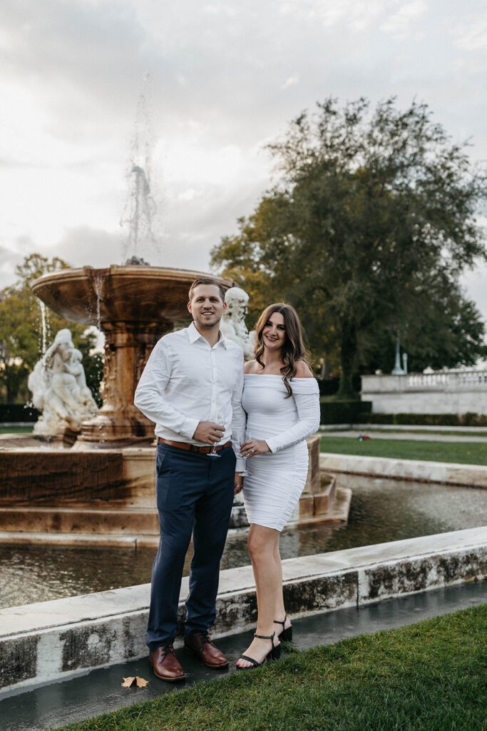 couple standing in front of fountain for engagement photos