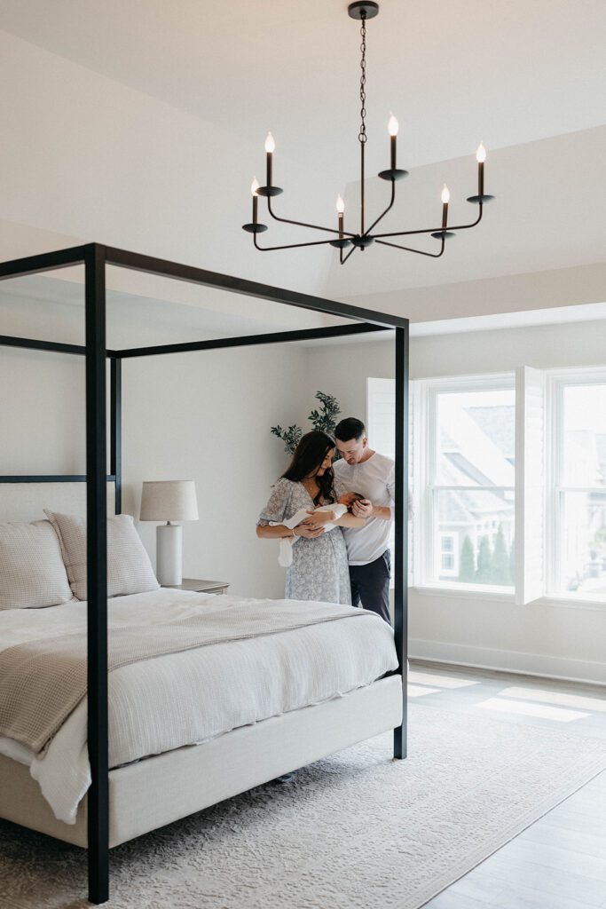 couple holding newborn baby in bedroom