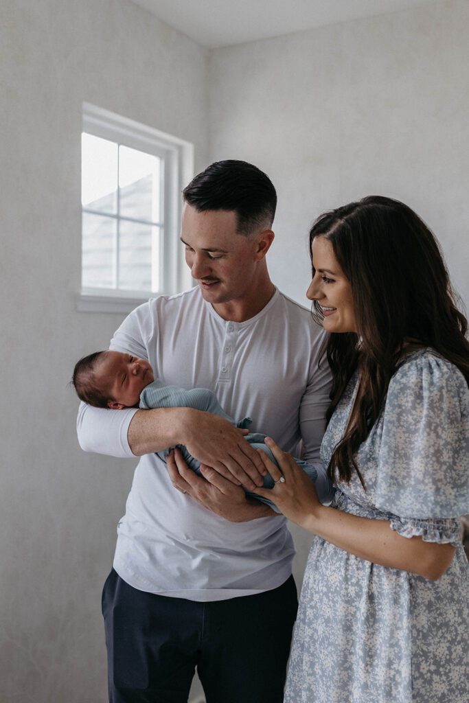 couple holding newborn baby in nursery