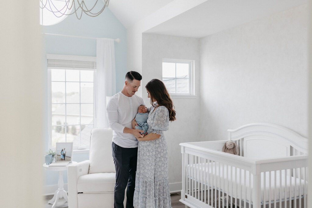 husband and wife posing for family photos with newborn in home