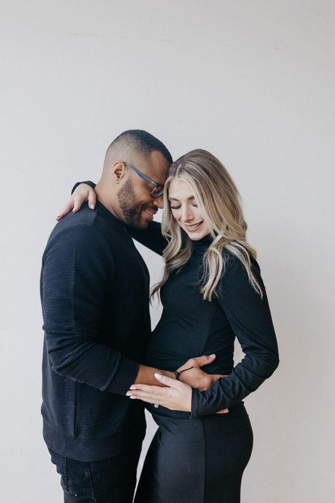 couple posing and smiling for maternity photos