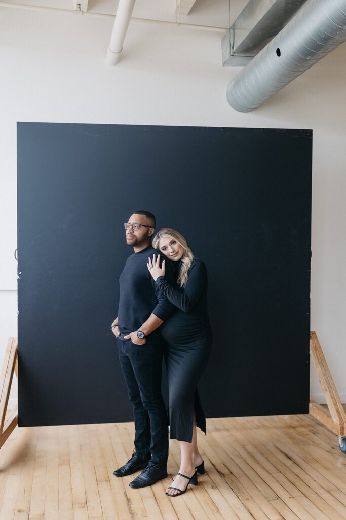 couple posing in front of backdrop for maternity photos
